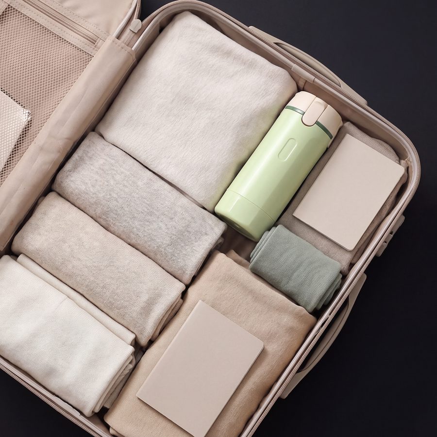 Lathrio travel dispenser packed in a carry-on suitcase next to folded clothes
